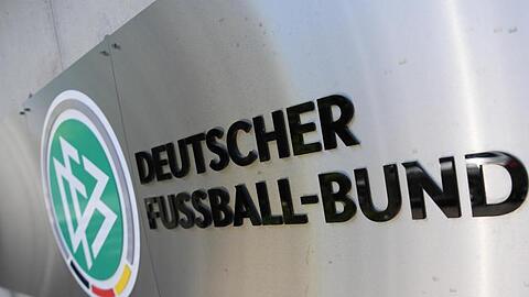 DFB-Logo und Schriftzug sind vor der Zentrale des Deutschen Fußball-Bundes (DFB) an einer Mauer platziert. Foto: Arne Dedert/dpa/Archivbild