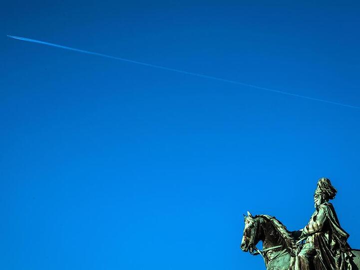 Über dem Kaiser-Wilhelm-Denkmal auf der Hohensyburg zieht ein Flugzeug seinen Kondensstreifen über einen wolkenlosen blauen Himmel.