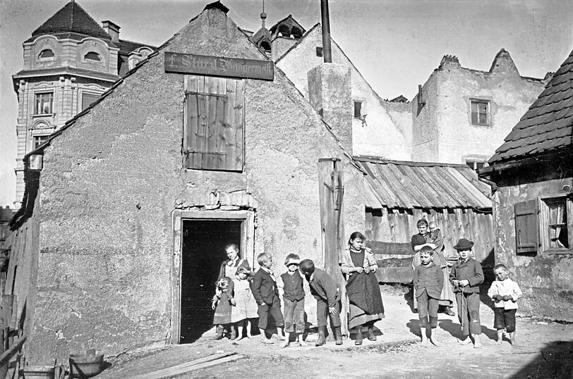 Eine Kinderschar hat sich aufgereiht 1895 vor einem bauf&auml;lligen Vorstadthaus in der Inneren Isarstra&szlig;e (heute: Reitmorstra&szlig;e). Vom hochnoblen Lehel ist hier noch (fast, siehe links hinten!) nichts zu sehen.