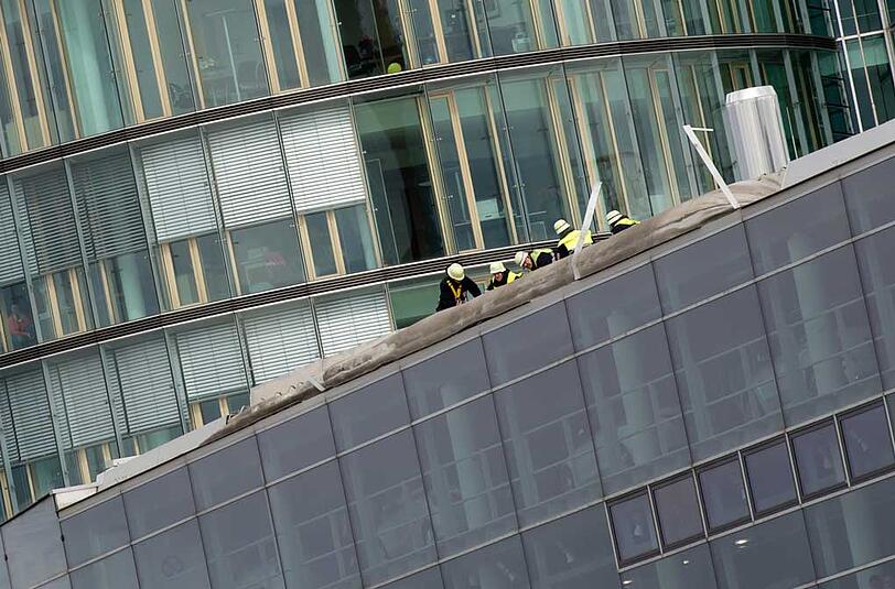 Feuerwehrleute begutachten die Schäden an einem Hausdach in München.