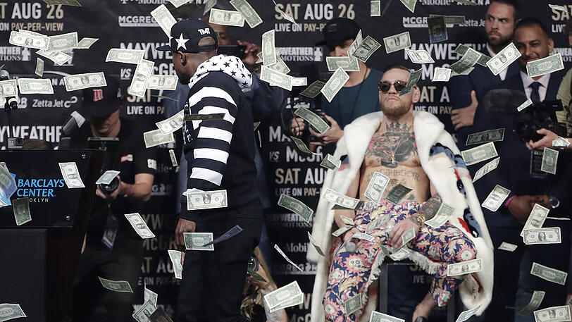 Floyd Mayweather bewirft seinen Kontrahenten Conor McGregor während der Pressekonferenz mit Geldscheinen.