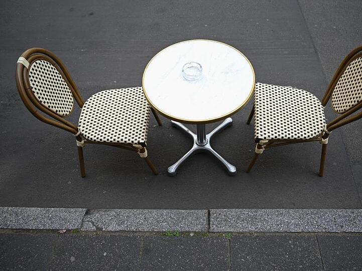 Ein Tisch mit zwei Stühlen steht auf der Töngesgasse in der Frankfurter Innenstadt vor einem Café.