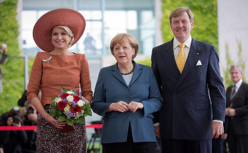 Mit Blumen, XXL-Hut und guter Laune: Königin Máxima und König Willem-Alexander werden von Angela Merkel (M.) begrüßt.