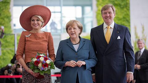 Mit Blumen, XXL-Hut und guter Laune: Königin Máxima und König Willem-Alexander werden von Angela Merkel (M.) begrüßt.