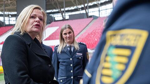 Nancy Faeser (SPD, l), Bundesinnenministerin, unterhält sich in der Leipziger Arena mit Vertretern der Polizei.