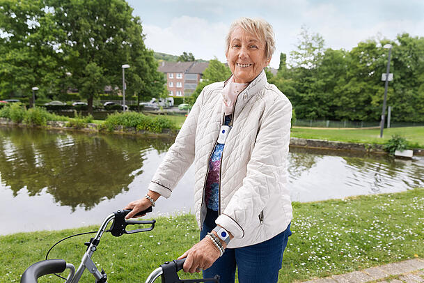 Diese Seniorin geht mit der Mobilversion eines Hausnotrufs spazieren.