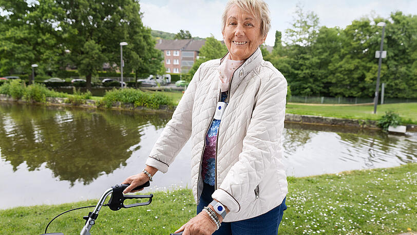 Diese Seniorin geht mit der Mobilversion eines Hausnotrufs spazieren.