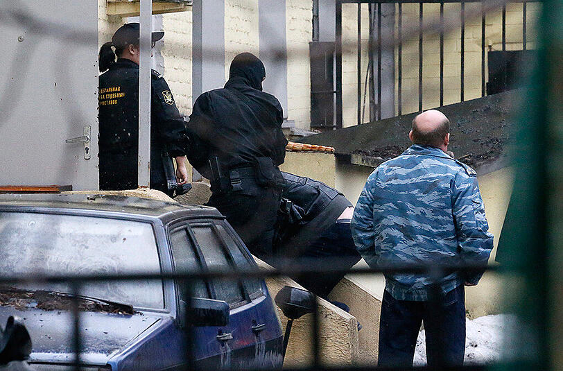 Russische Polizisten führen einen Mann ab, der am Mord an Boris Nemzow beteiligt gewesen sein soll. Einer der Tatverdächtigen soll jetzt gestanden haben.
