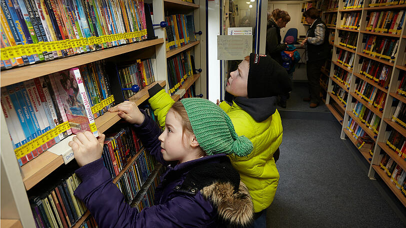 Kinder stöbern in einem Bücherbus nach Büchern. (Archivbild)