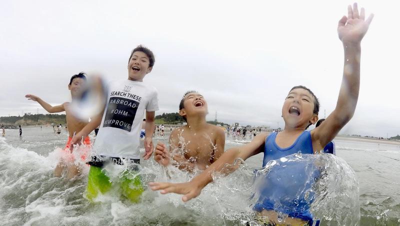 Kinder spielen im Wasser: Nach der Nuklearkatastrophe von Fukushima wurde der Strand zum ersten Mal wieder für Besucher zugelassen. Kinder spielen im Wasser: Nach der Nuklearkatastrophe von Fukushima wurde der Strand zum ersten Mal wieder für Besucher zugelassen.