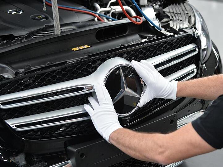 Ein Mitarbeiter von Mercedes-Benz bringt den Stern an einem Auto der C-Klasse an.