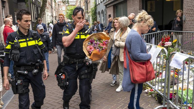 Polizisten bringen einen Blumenstrauß zu dem Blumenmeer für den Reporter Peter R. de Vries in der Leidswarsstraat.