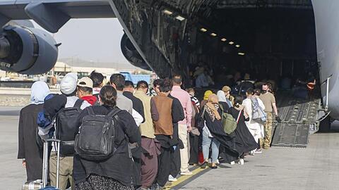 Menschen stehen auf dem Rollfeld und gehen an Bord eines US-Transportflugzeugs von Typ C-17 Globemaster III während ihrer Evakuierung am Hamid Karzai International Airport in Afghanistan.