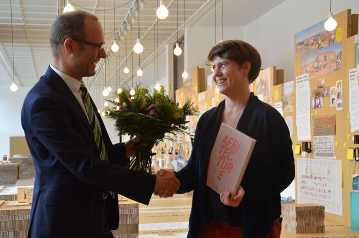 Andres Lepik begrüßte die 50.000ste Besucherin der Ausstellung "Afritecture &ndash; Bauen mit der Gemeinschaft", Fiona Hemmi.