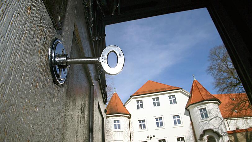 Im Schloss der geöffneten Türe des Eingangsbereiches der Justizvollzugsanstalt in Aichach steckt ein Schlüssel. Ein Beamter des Gefängnisses wurde nun zu einer Geldstrafe verurteilt, weil er einen Insassen geschlagen hatte. (Archivbild-Illustration)