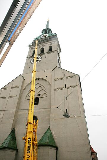Ein großer gelber Kran ragt vor dem Alten Peter in Richtung Himmel...
