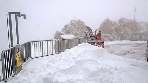 Der erste Neuschnee auf der Zugspitze: Eine Mitarbeiterin räumt die Aussichtsplattform mit einem Fahrzeug.