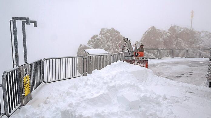 Der erste Neuschnee auf der Zugspitze: Eine Mitarbeiterin räumt die Aussichtsplattform mit einem Fahrzeug.