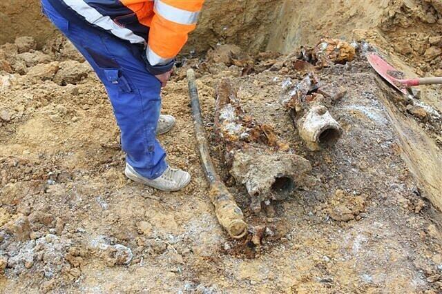 Ein Bauarbeiter steht an der Baustelle neben den Resten eines Flugzeugwracks, die zuvor aus dem Erdreich geborgen wurden.