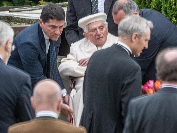 Der emeritierte Papst Benedikt XVI. (M) besucht das Grab seiner Eltern und Schwester bei Regensburg. Foto: Armin Weigel/dpa