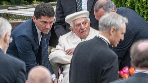 Der emeritierte Papst Benedikt XVI. (M) besucht das Grab seiner Eltern und Schwester bei Regensburg. Foto: Armin Weigel/dpa