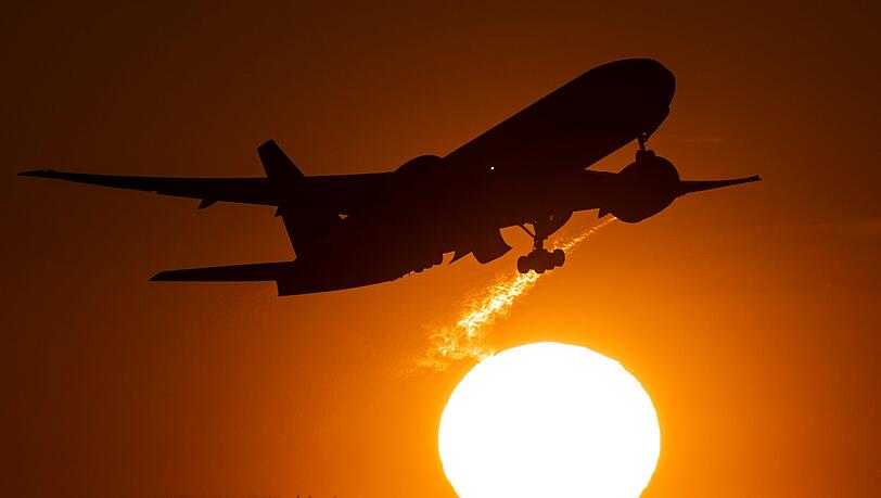 Eine Passagiermaschine hebt vor der untergehenden Sonne vom Flughafen Frankfurt ab.