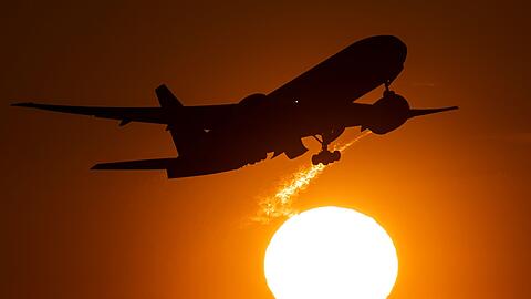 Eine Passagiermaschine hebt vor der untergehenden Sonne vom Flughafen Frankfurt ab.