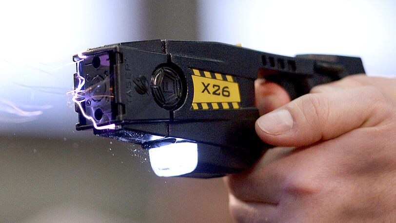Ein Taser verschießt kleine, durch einen Draht verbundene Pfeile. Ein Taser verschießt kleine, durch einen Draht verbundene Pfeile.