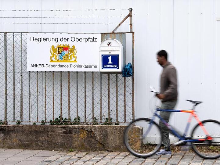 Ein Mann mit einem Fahrrad geht an einem Ankerzentrum. Foto: Lino Mirgeler/Archivbild