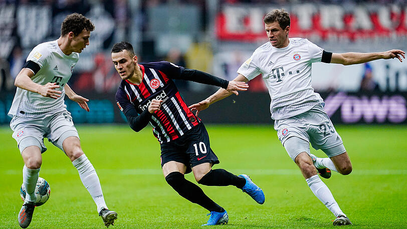 Benjamin Pavard (l.), Frankfurts Filip Kostic (m.) und Münchens Thomas Müller (r.) kämpfen um den Ball.