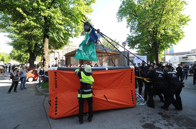 Andere Tierschützer sitzen auf Metallgestellen im Weg. Manche stellen sich den Viehtransportern mit nacktem Oberkörper in den Weg.
