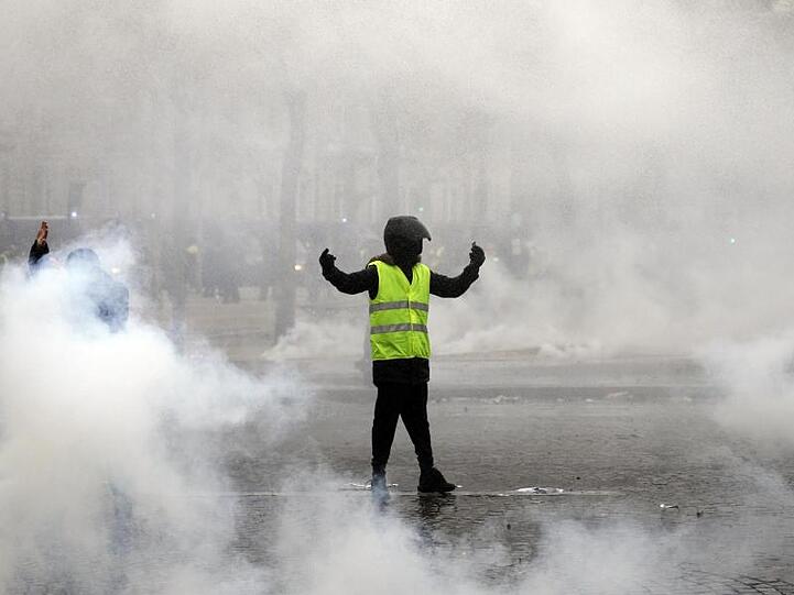 Ein Demonstrant in gelber Weste steht in Paris inmitten von Rauchschwaden.