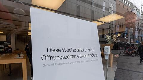 Ein Schild im Apple Store München verweist auf geänderte Öffnungszeiten. Foto: Peter Kneffel/dpa