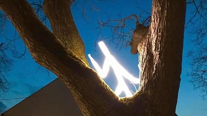 Ein Lichtmensch sitzt im Baum.