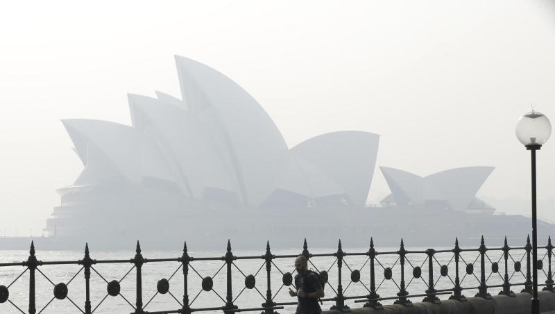 Ein Jogger läuft am Morgen, während Rauchschleier über der Sydney Opera House hängt. Ein Jogger läuft am Morgen, während Rauchschleier über der Sydney Opera House hängt.