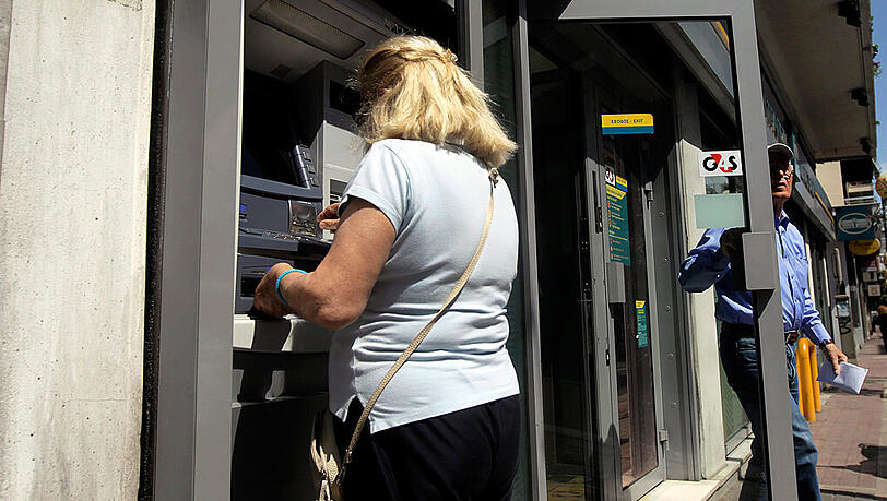 Eine Frau in Athen hebt Geld an einem Automaten ab. Immer mehr griechische Verbraucher ziehen Bank-Einlagen in großer Höhe ab. Eine Frau in Athen hebt Geld an einem Automaten ab. Immer mehr griechische Verbraucher ziehen Bank-Einlagen in großer Höhe ab.