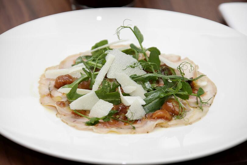 Lauwarme Porchetta vom Poltinger Spanferkel mit Dörrobstvinaigrette, Rucola und Pecorino: Die herbe Note des hauchdünn aufgeschnittenen Ferkels und des Rucolas fängt die leichte Süße der Dörrobstvinaigrette auf. Der Grüne Silvaner vom Gut Wernersbach in der Region Rheinhessen kann diesem Aromenspiel mit feiner Mineralität und Birnenduft einen eigenen Charakter entgegensetzen.