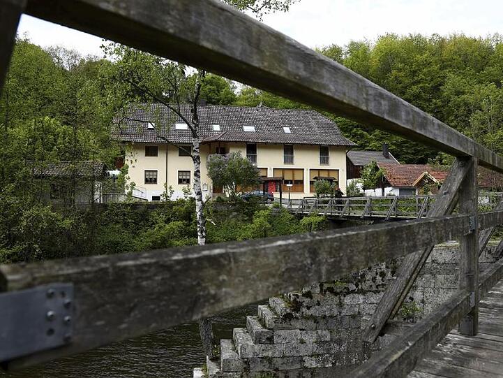 Blick durch das Geländer einer Brücke auf die Pension, in der die drei Toten gefunden wurden.