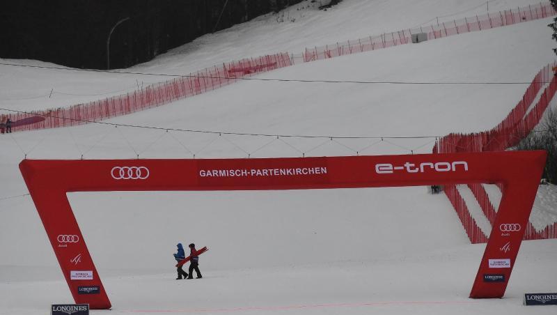 Zwei Helfer gehen in Garmisch hinter dem Zielbogen vorbei. Das zweite Training wurde wegen zu schlechtem Wetters abgesagt.
