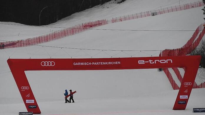 Zwei Helfer gehen in Garmisch hinter dem Zielbogen vorbei. Das zweite Training wurde wegen zu schlechtem Wetters abgesagt.
