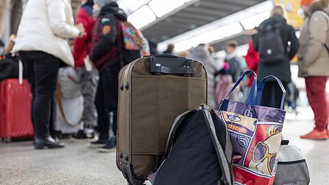 Flüchtlinge aus der Ukraine stehen mit Gepäck am Münchner Hauptbahnhof.