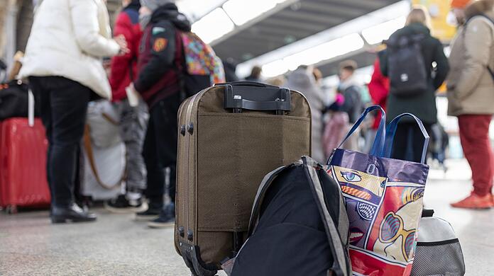 Flüchtlinge aus der Ukraine stehen mit Gepäck am Münchner Hauptbahnhof.