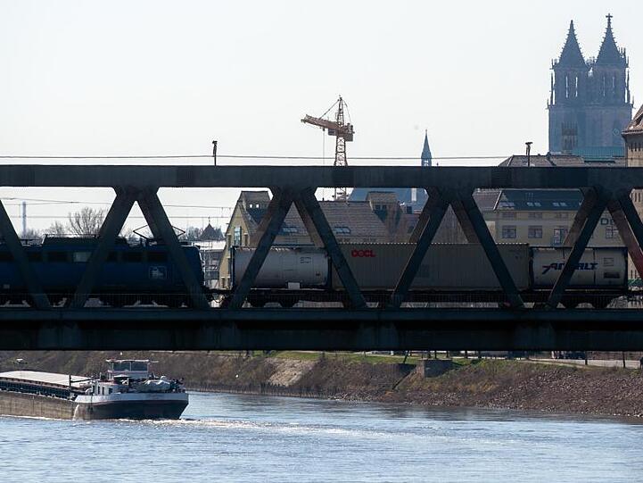 Ein Güterzug fährt über eine Elbebrücke in Magdeburg. Die Coronavirusepidemie belastet das Wirtschaftsleben schwer.