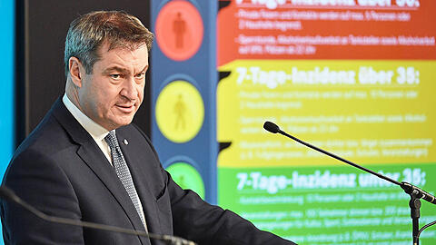 Markus Söder gestern nach der Sitzung des bayerischen Kabinetts. Im Hintergrund: ein Überblick über die neuen Maßnahmen.