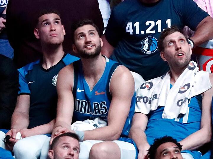Dwight Powell (l-r), Maximilian Kleber und Dirk Nowitzki verfolgen in einer Auszeit einen Film auf dem Videoawürfel im Stadion.