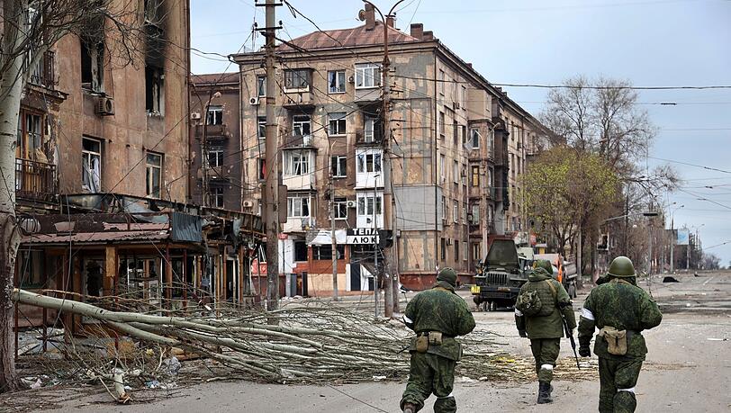 Soldaten der Miliz der "Volksrepublik" Donezk gehen an beschädigten Wohnhäusern in Mariupol vorbei.