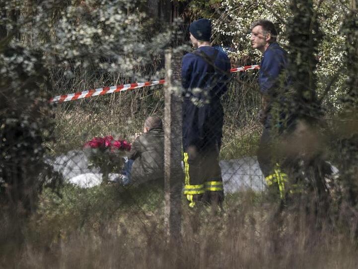 Ein Mann trauert an der Absturzstelle. Zwei Feuerwehrleute stehen neben ihm.