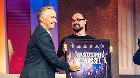 "Lass dich &uuml;berwachen!": Moderator Jan B&ouml;hmermann &uuml;berreicht einen Preis an einen Kandidaten.