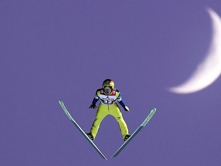 Der japanische Skispringer Noriaki Kasai springt vor dem Mond. Foto: Hendrik Schmidt/Archiv