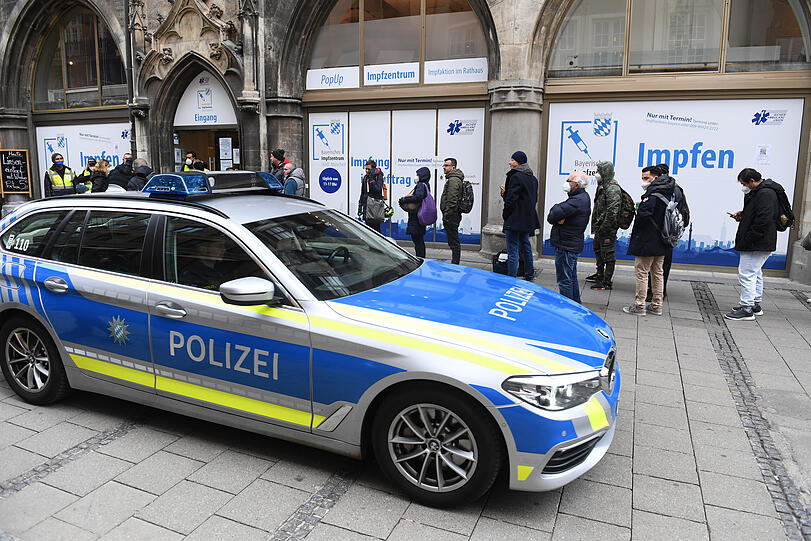Eine Polizeistreife fährt am Samstag an der langen Warteschlange vor der Impfstation im Münchner Rathaus vorbei.
